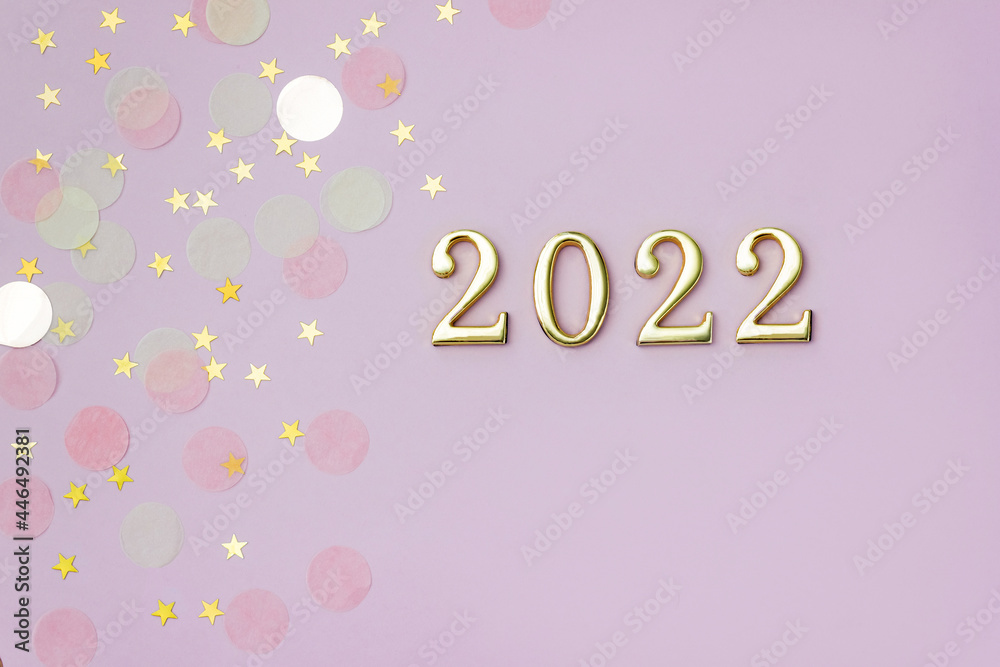 Golden number 2022 on pink background decorated with pastel starry confetti. New Year celebration concept. Flat lay
