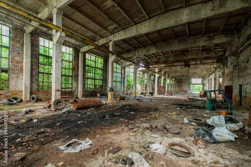 a landfill in a dilapidated building of an old production workshop with broken windows, dirty walls, remnants of equipment and old tires