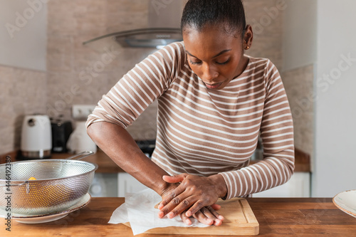 Black woman preparing tostones at table in kitchen photo