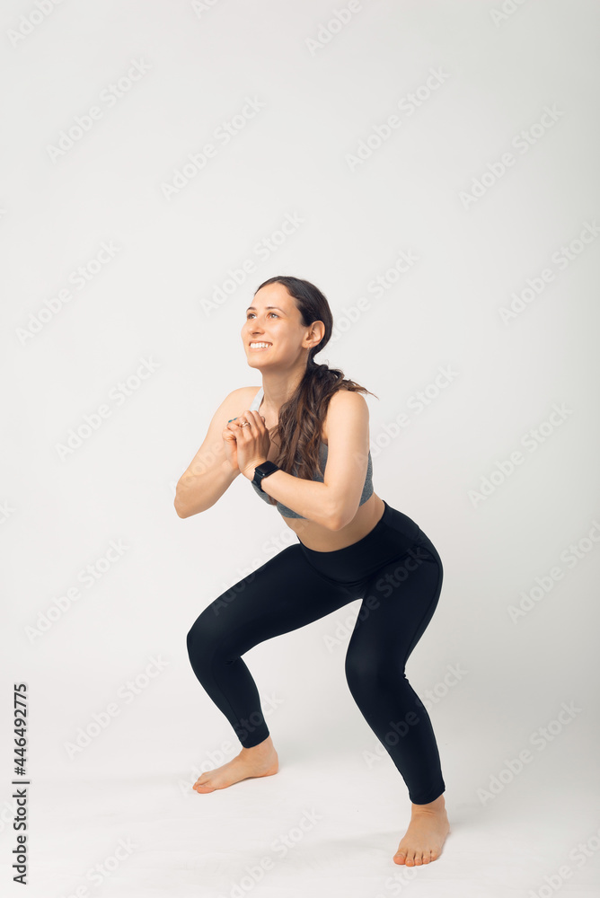 Photo of sporty woman squatting doing sit ups over white background