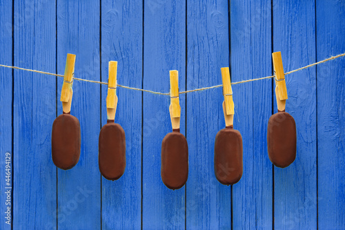 many chocolate ice creams hanging on rope near deep blue background. hot summer. delicious chilling food concept