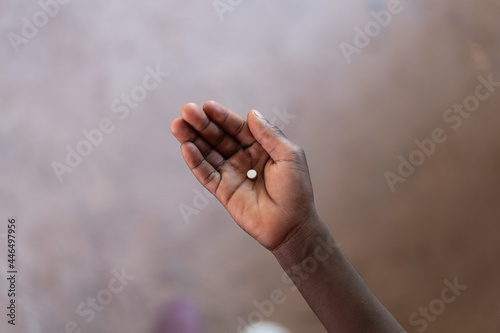 African Boy Holding Medicine Pill in his Hand to show Medical Treatment © Riccardo Niels Mayer