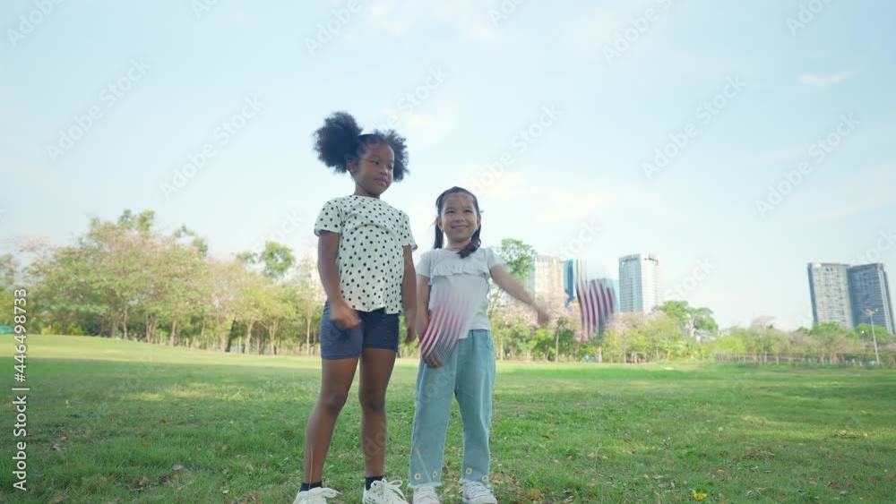 Holiday concept of 4k Resolution. The girls are waving American flags in the garden. Holiday concept of 4k Resolution. The girls are waving American flags in the garden.