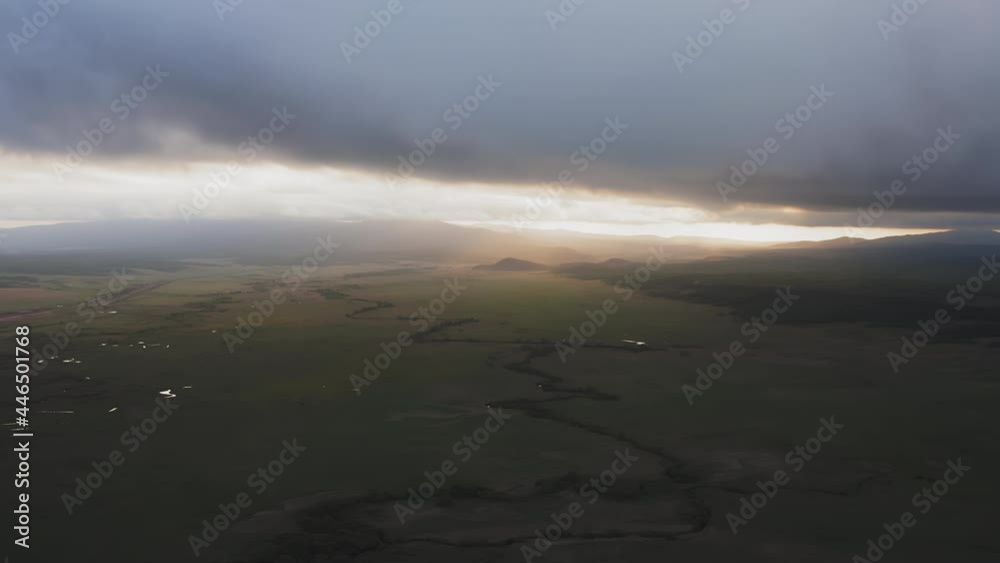 Drone view of a sunset in a valley with a river and mountain ranges Drone view of a sunset in a valley with a river and mountain ranges