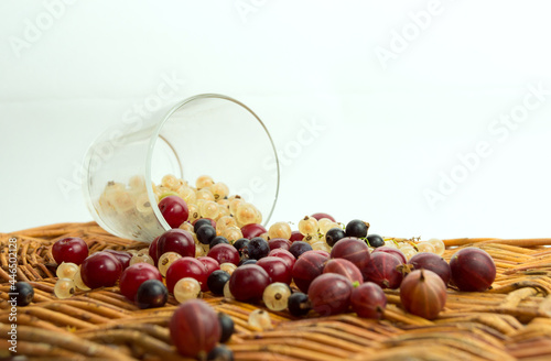 An explosion of different berries. Photo of strawberries, blueberries, gooseberries, in a transparent glass on a white wooden table. The view is straight. Soft Focus Product
