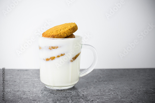 Fotografie Stack of round cookies soaked in milk in a transparent glass cup