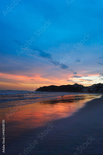 Sunset on the beach with the reflection of the red sky in the water, mexican pacific, acapulco diamante