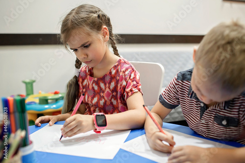 A lefty girl and righty boy writing at the same desk and nudge each other with elbows, international left-hander day celebration, only lefties understand photo