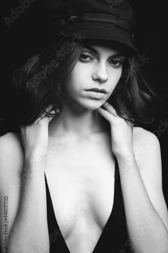 Girl on a black background. Low key. Nice young girl in a hat on a black studio background.