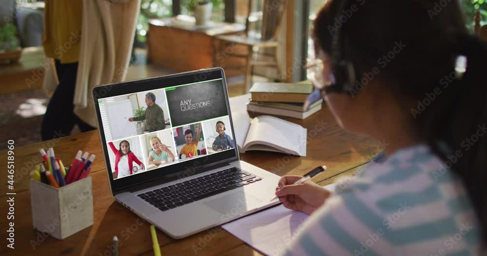 Schoolgirl using laptop for online lesson at home, with diverse teacher and class on screen