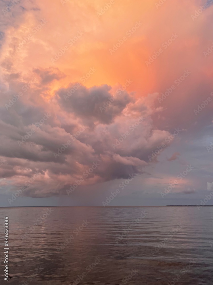 Burst of large colorful sunset clouds reflecting onto bay water Burst of large colorful sunset clouds reflecting onto bay water