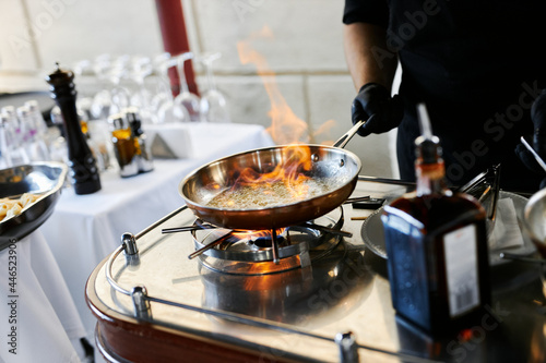the chef prepares orange caramel on an open fire on the terrace of the restaurant