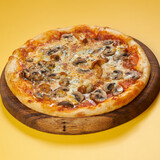 rustic pizza with mushrooms on wooden board and yellow background