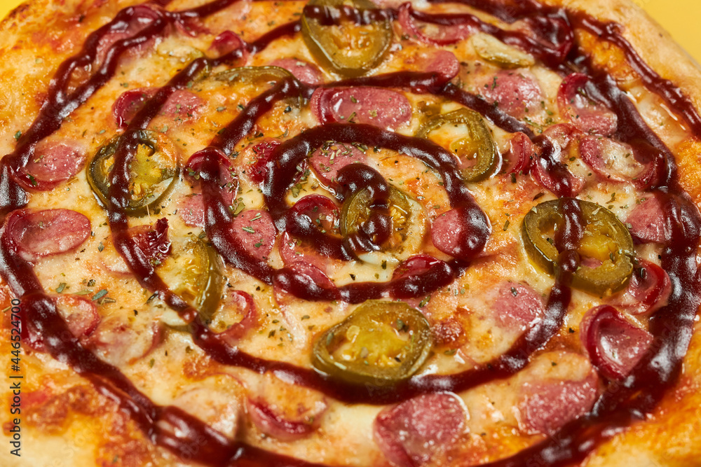 rustic pizza with sausages and jalapena on wooden board and yellow background rustic pizza with sausages and jalapena on wooden board and yellow background