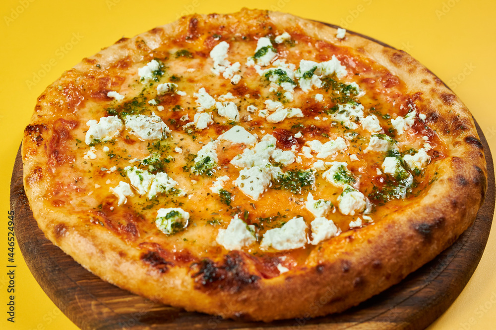 rustic pizza with feta cheese and herbs on wooden board and yellow background rustic pizza with feta cheese and herbs on wooden board and yellow background