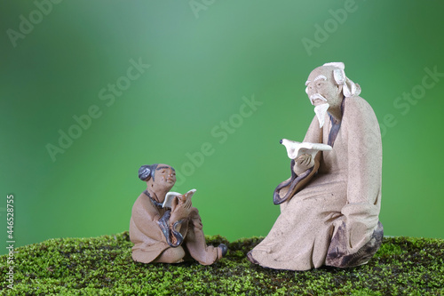 Learn Chinese language concepts : Clay sculptures of Confucius with students reading book. Selective focus, blurred background with copy space photo