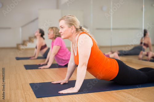 Portrait of active senior woman practicing yoga with group at dance studio