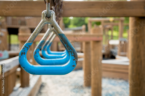 Blue trapeze monkey bar handles that are rusty