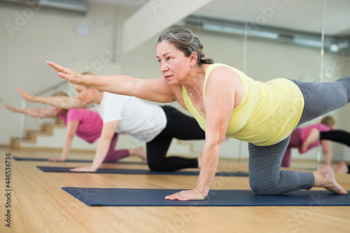 Elderly woman maintaining mental and physical health attending group yoga class at studio