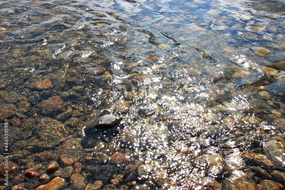 brown and gray stones in the water with the reflected sun brown and gray stones in the water with the reflected sun