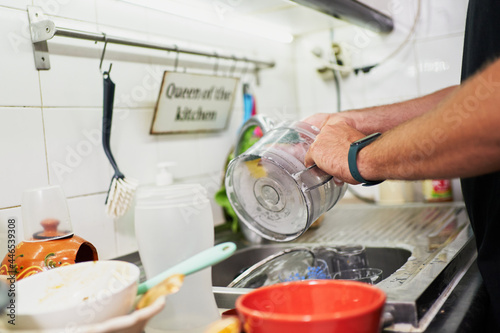 Young unrecognizable man washing dishes. Everyday chores