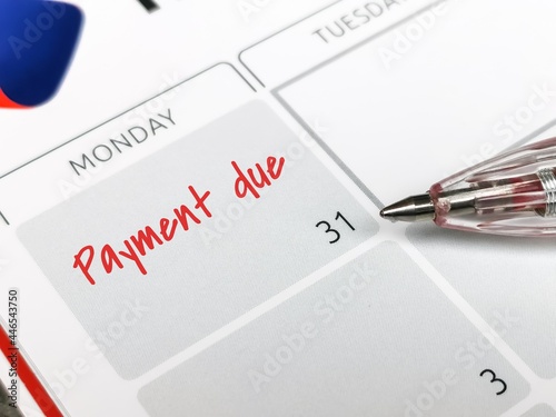 Reminder concept of payment. Close up text payment due written on calendar with a pen. Selective focus. photo