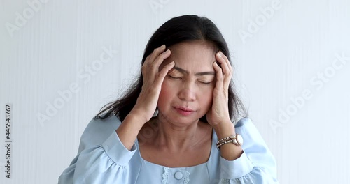 A senior Asian woman suffered and pain from headaches using hand holding head. Concept of older person health care. photo