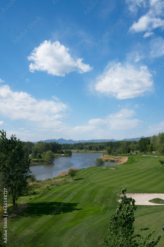 Riverside golf course under blue sky and white clouds