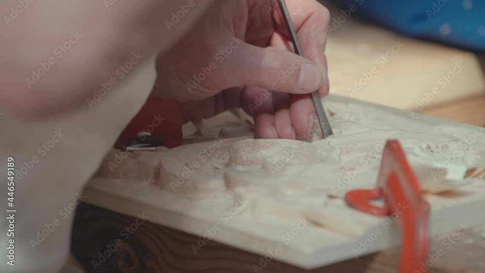 Close-up of woodworker hands chiseling accurately a wooden tablet taking care of a detail of design. Slow motion Close-up of woodworker hands chiseling accurately a wooden tablet taking care of a detail of design. Slow motion