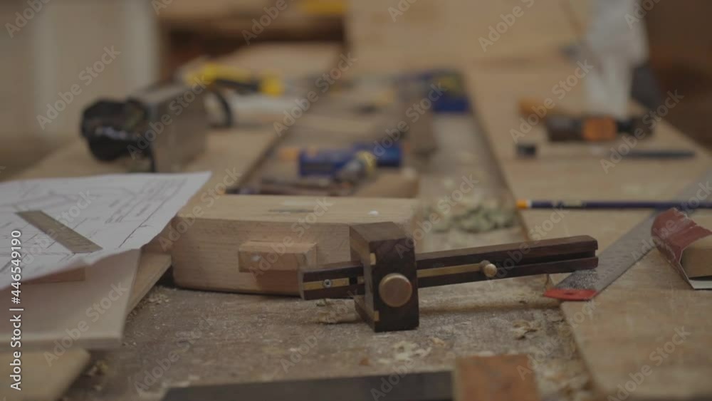 Ascending view of a carpenter's worktable with different tools and an hand taking a sandpaper. Slow motion Ascending view of a carpenter's worktable with different tools and an hand taking a sandpaper. Slow motion