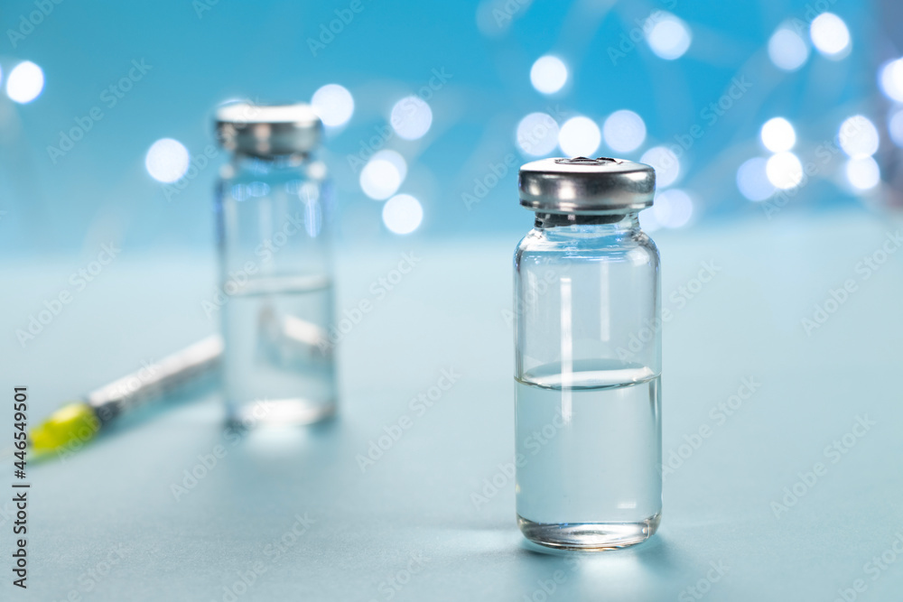 Two bottles of vaccine and syringe injection on blue background. Concept of prevention, immunization and treatment from infection. Medicine infectious concept. Close up. Two bottles of vaccine and syringe injection on blue background. Concept of prevention, immunization and treatment from infection. Medicine infectious concept. Close up.