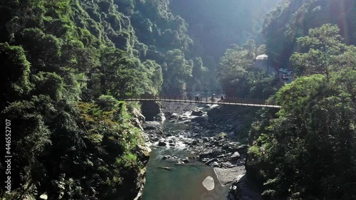 Aerial flight of natural rocky stream and tourist walking over bridge during sunny day in national park of wulai district in Taiwan,Asia. photo