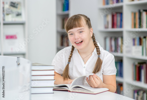 Happy girl with syndrome down at library. Education for disabled children concept