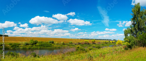 Panoramic summer rural landscape with beautiful river and farm fields in sunny august day.