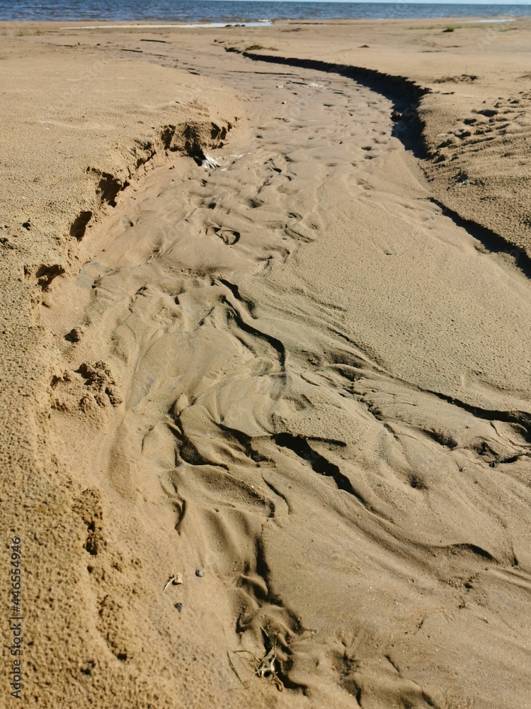 Obraz premium sandy shore of the lake prints of human footprints and water flows