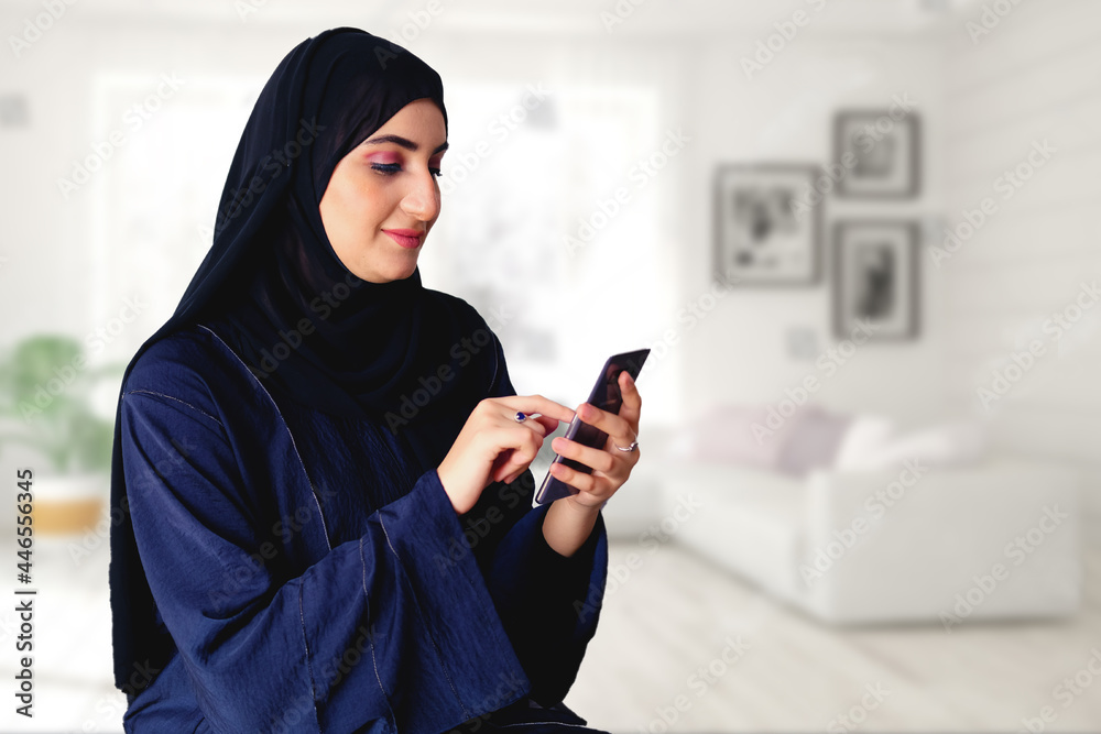 Arabic woman using a mobile smartphone wearing Abaya Hijab traditional women's wear in the Middle East Arabic woman using a mobile smartphone wearing Abaya Hijab traditional women's wear in the Middle East