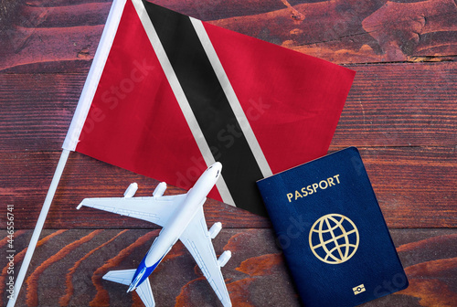 Flag of Trinidad and Tobago with passport and toy airplane on wooden background. Flight travel concept 