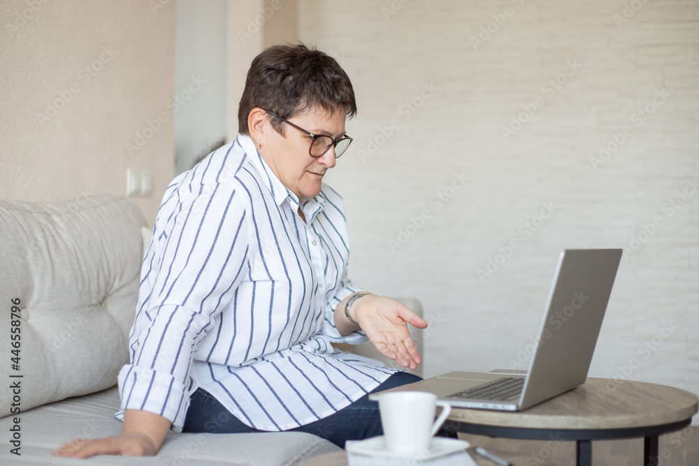 middle aged woman working by laptop and drinking coffee at home. middle aged woman working by laptop and drinking coffee at home.
