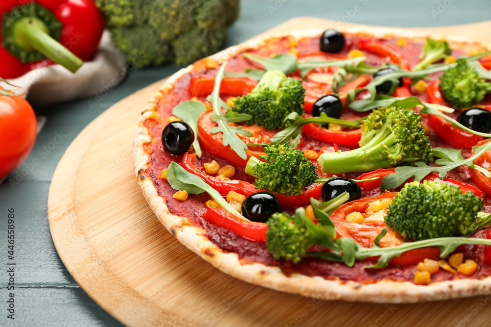 Board with tasty vegetarian pizza on color wooden background, closeup Board with tasty vegetarian pizza on color wooden background, closeup