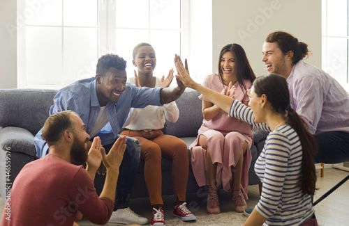 Wall Mural Group of happy young multiethnic people sitting in living room and having fun together