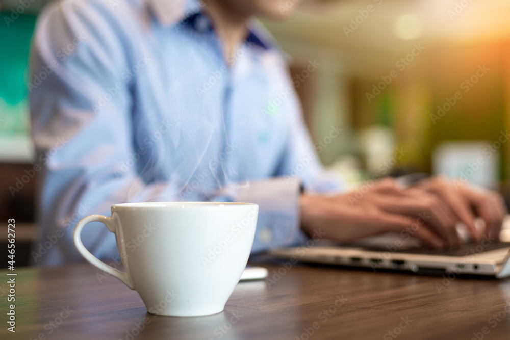 Blurred of cup of hot coffee with businessman use computer Blurred of cup of hot coffee with businessman use computer