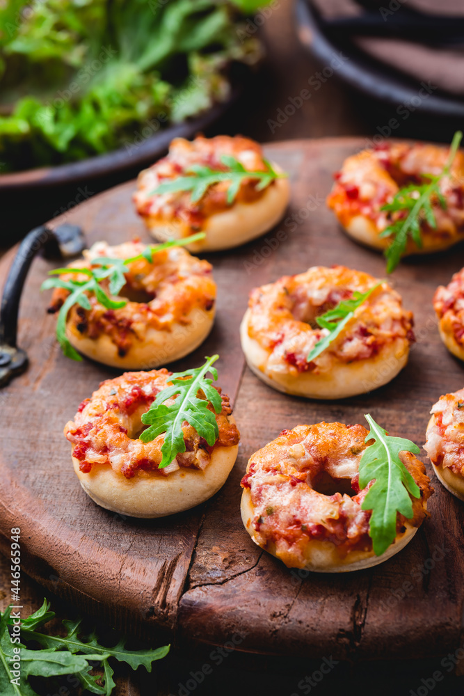 Small pizza in donut shape with rocket (arugula) and fresh salad Small pizza in donut shape with rocket (arugula) and fresh salad