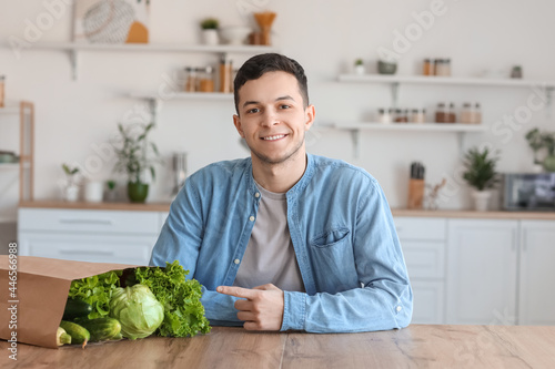 Young man with fresh vegetables in kitchen