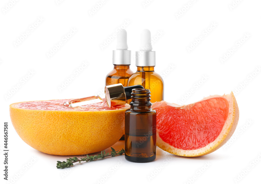 Bottles of essential oil and grapefruits on white background Bottles of essential oil and grapefruits on white background