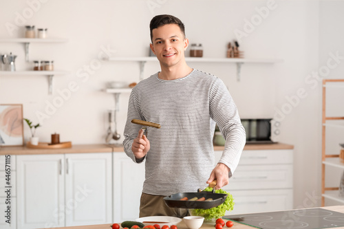 Young man frying tasty saus...