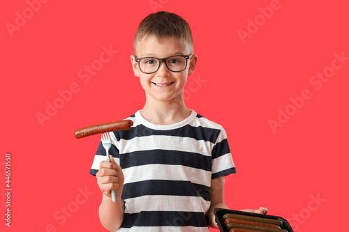 Little boy with tasty sausages on color background photo