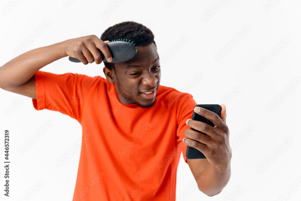 African American combing his head with a phone in his hands head care African American combing his head with a phone in his hands head care