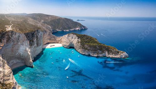 Fototapeta Naklejka Na Ścianę i Meble -  Wide aerial view to the famous Navagio shipwreck beach on the island of Zakynthos, Ionian sea, Greece, with turquoise sea and boats approaching