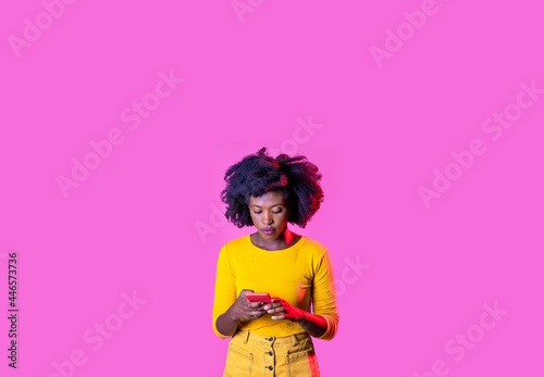 Isolated black young woman using smartphone watching video surfing web on advertising copyspace background