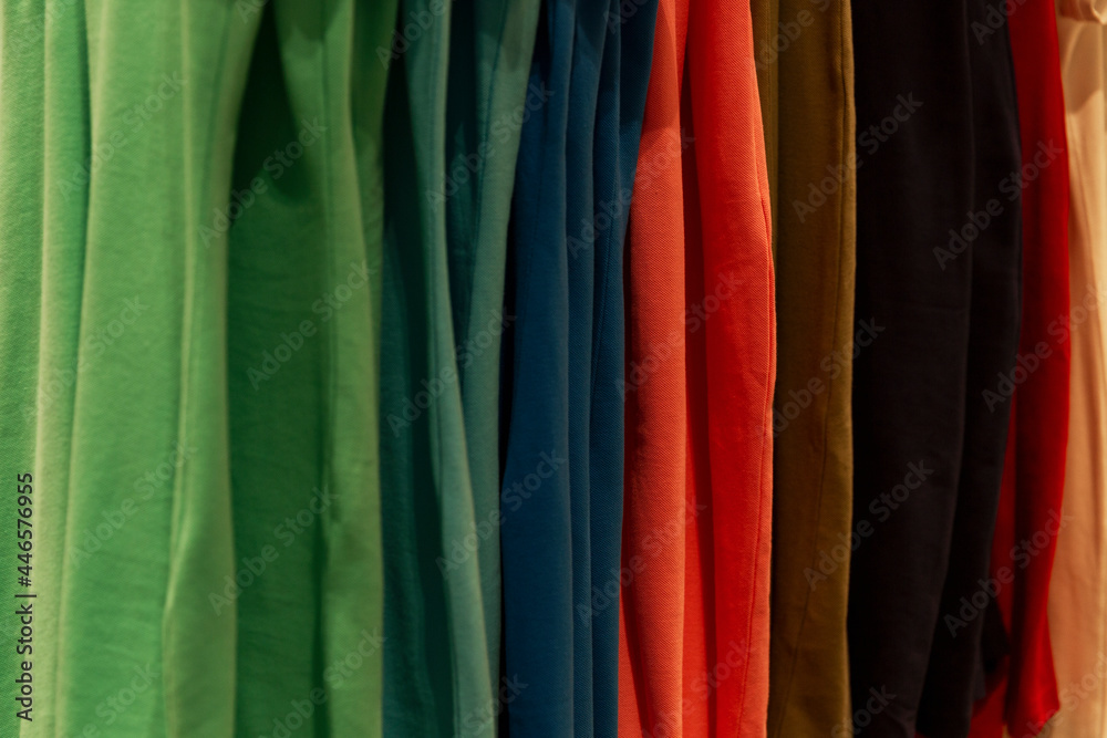 Multicolored cotton T-shirts on a hanger in a store. Close-up.